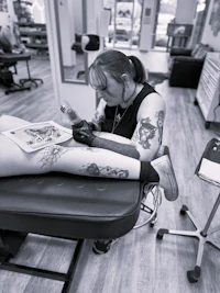 a woman getting a tattoo in a black and white photo