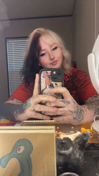 a woman with tattoos taking a selfie in a mirror